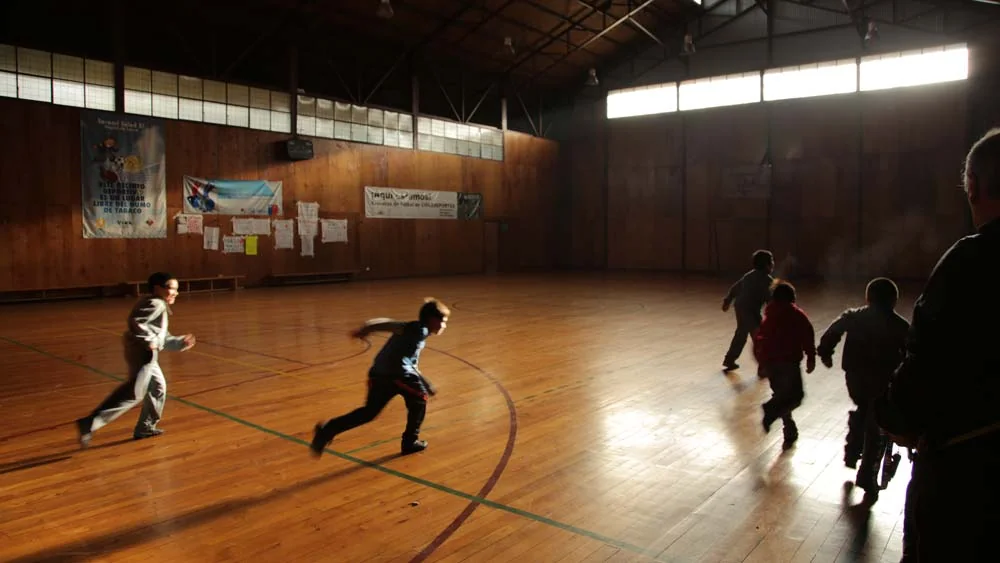 Children taking part in a Recreo Espacial movement activity in a school gymnasium